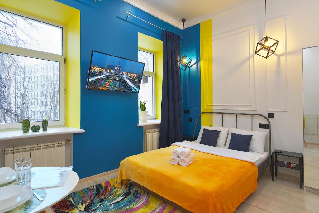 Dormitorio azul y amarillo con cama y mesa en Axis.Moscow Island en Moscú