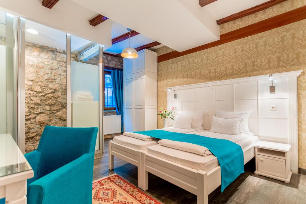 een slaapkamer met een bed en een blauwe stoel bij Hotel-Restaurant Kriva Ćuprija in Mostar