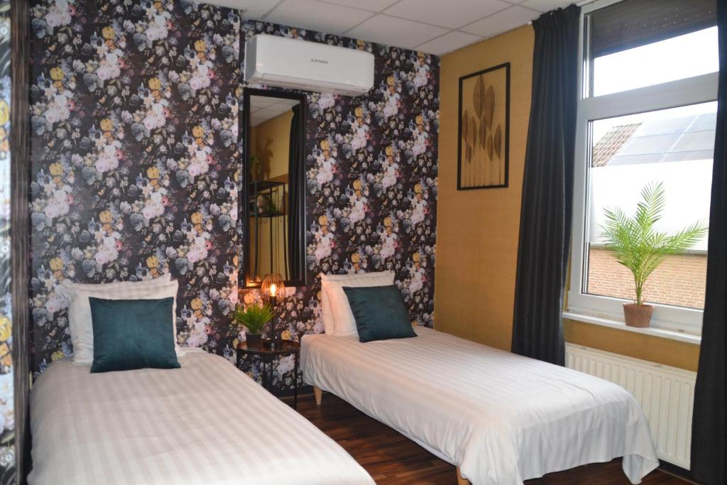 2 camas en una habitación con papel pintado floral en Hotel Restaurant Cafe Houben, en Nunhem
