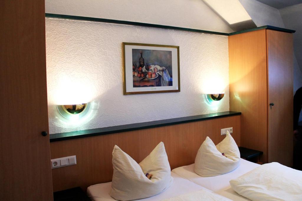 a hotel room with a bed with white pillows at Hotel-Landgasthof Grüner Baum - Dittigheim in Tauberbischofsheim