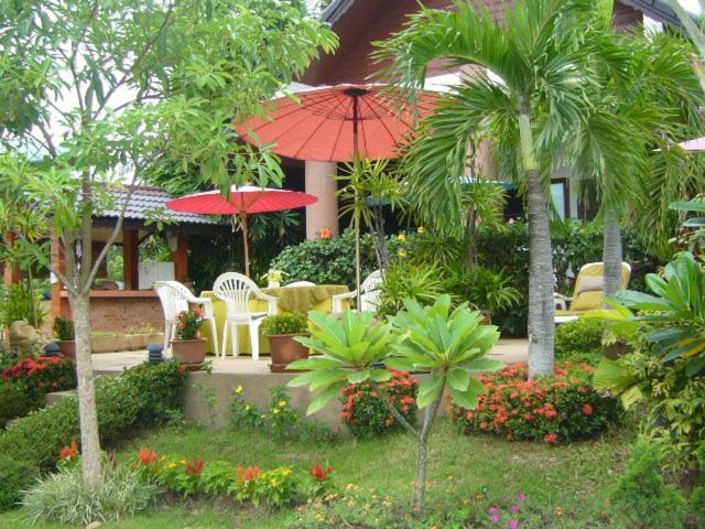 un jardín con sillas y sombrillas frente a una casa en Saku Boutique Homestay, en Saraphi