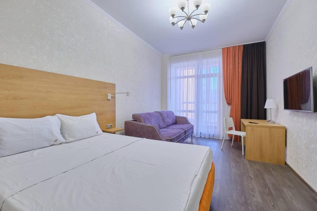 um quarto de hotel com uma cama grande e um sofá em Апартаменты Петровские однокомнатные Трифонова 22 em Tomsk
