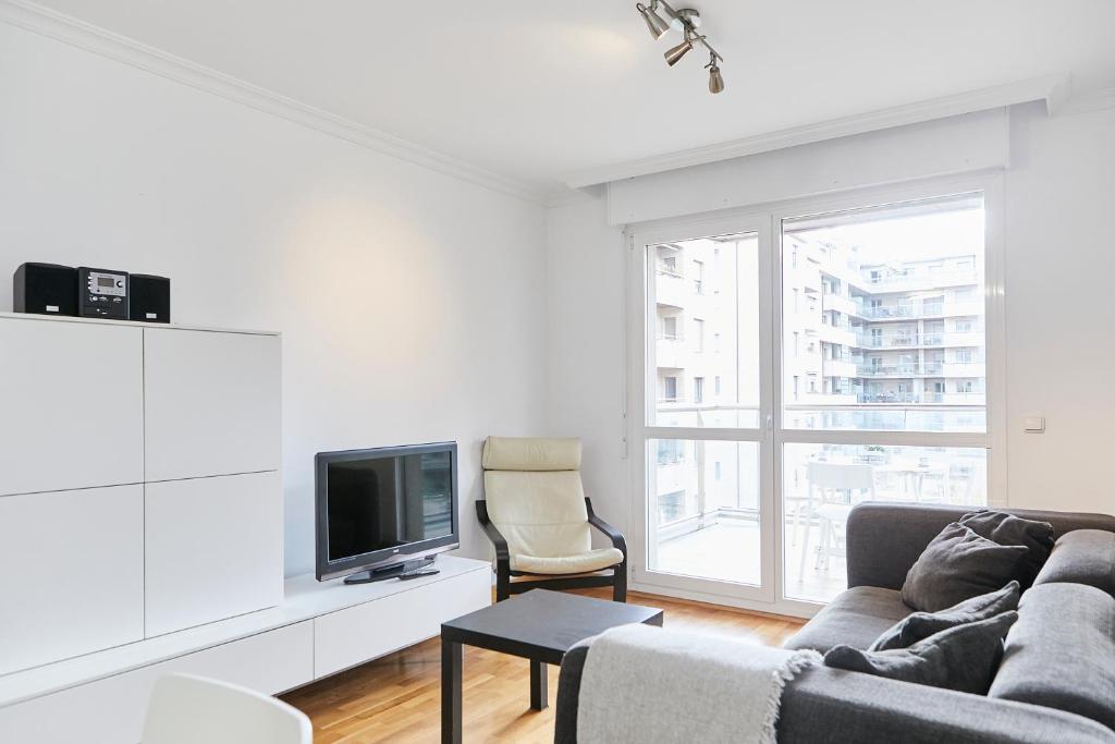 uma sala de estar com um sofá e uma televisão em Urumea 4 - Apartamento con parking em San Sebastián
