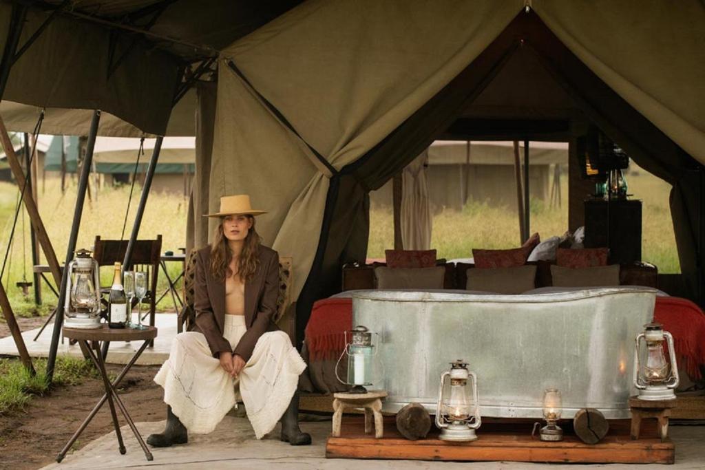 Una mujer está sentada en una tienda. en Pumzika Luxury Safari Camp, en Banagi