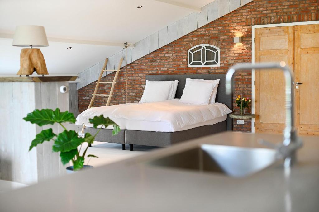 a bedroom with a bed in a brick wall at Loft in de Polder (L) in Grootschermer