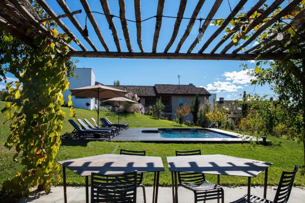 un patio con 2 tavoli, sedie e piscina di ROSTAGNI1834: VILLA WITH 2 APTS AND POOL IN THE BAROLO REGION a Novello