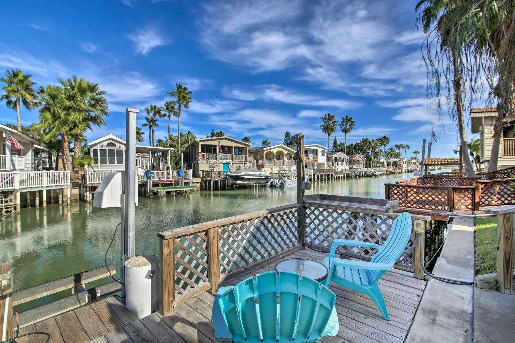 a deck with two blue chairs and a view of the water at Cozy Waterfront Port Isabel Cottage with Deck! in Port Isabel
