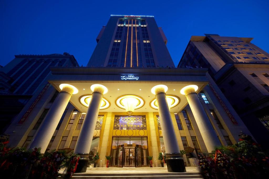 a building with columns with a tall building in the background at Dynasty International Hotel Dalian in Jinzhou