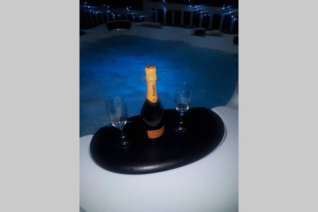 Una botella de champán y dos copas en una mesa. en Hillingworth's Hot Tub Retreat - St Cyrus, en Garvock