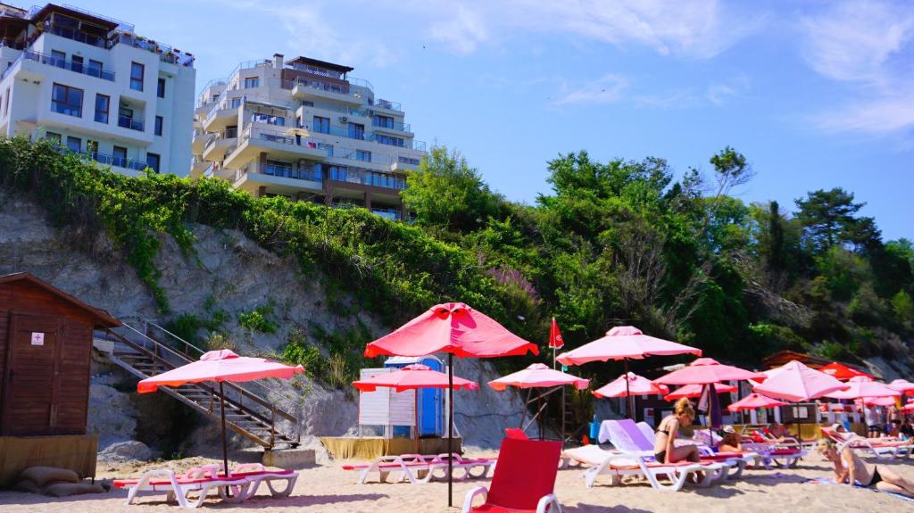 een stel parasols en stoelen op een strand bij Апартаменти Бяла Клиф на плажа - Apartments Byala Cliff First Line in Byala