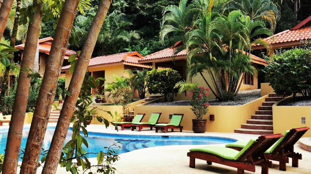 a resort pool with chaise lounge chairs and palm trees at Hotel Ritmo Tropical - Pool and Breakfast in Santa Teresa Beach
