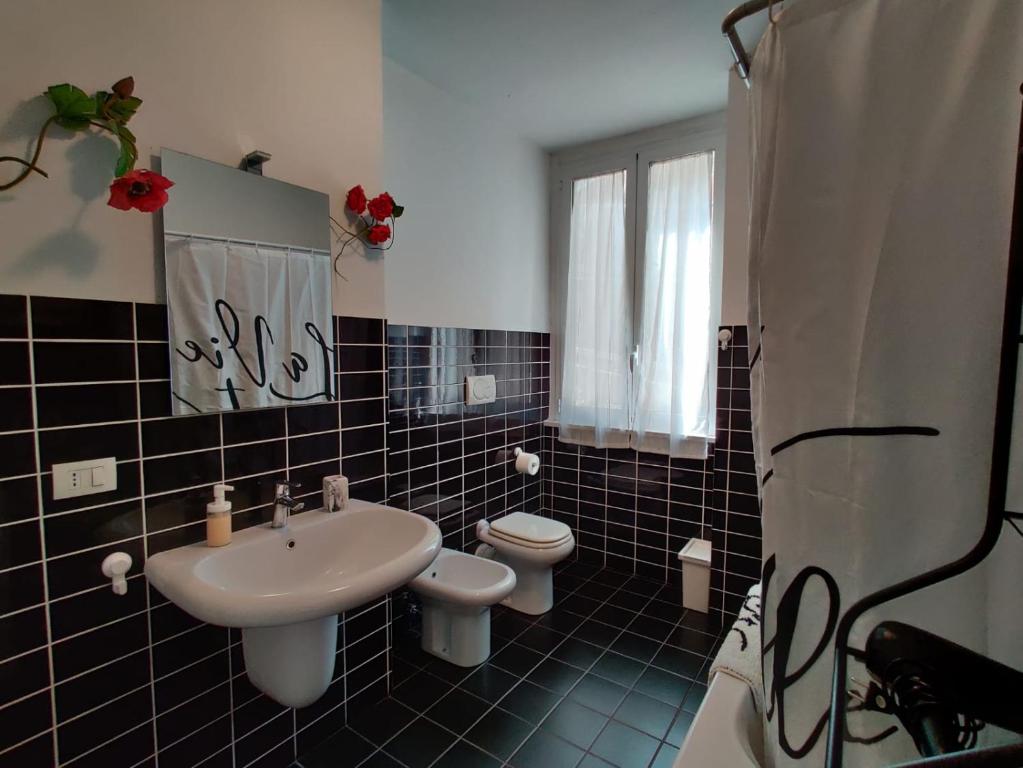 czarno-biała łazienka z umywalką i toaletą w obiekcie Wow Home - 175 mq - posteggio privato - davanti porto traghetti - fino a 10 posti letto w Genui