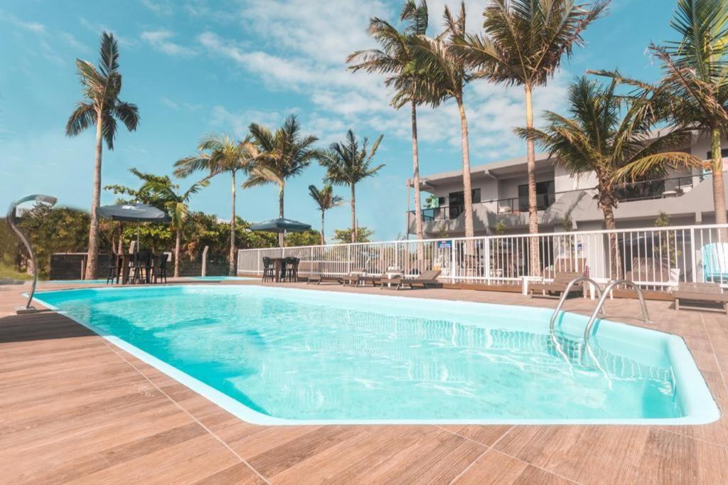 a swimming pool with palm trees and a building at Pousada Morada da Praia - Balneário Camboriú in Balneário Camboriú