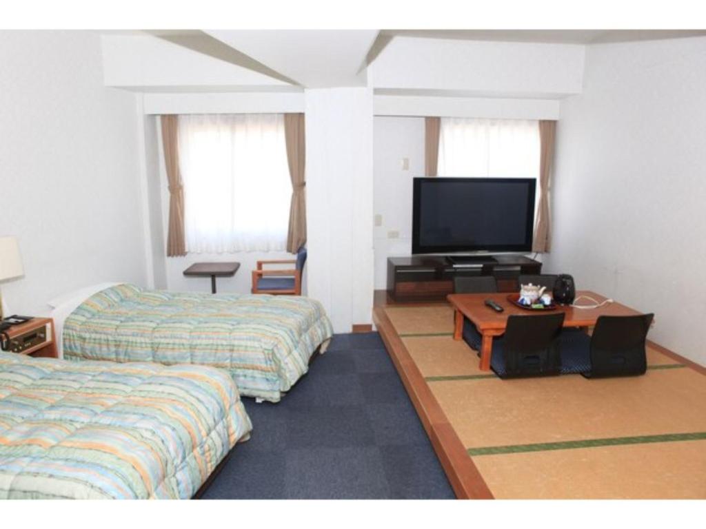 een kamer met 2 bedden en een flatscreen-tv bij Hotel Kokusai Plaza - Vacation STAY 09930v in Naha