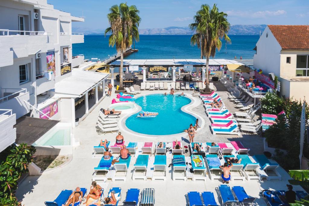 un'immagine di una piscina in un resort con persone sedute su sedie di Quayside Village Hotel a Kávos