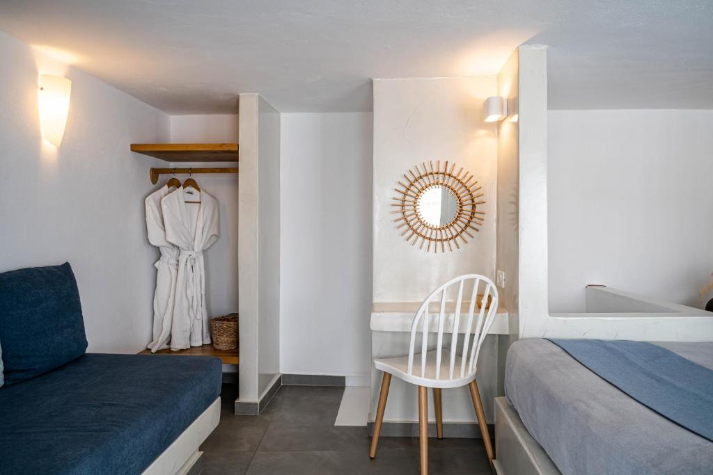 a bedroom with a bed and a chair and a mirror at Galatia Villas in Fira