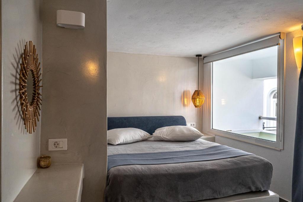 a bedroom with a bed with a large window at Galatia Villas in Fira