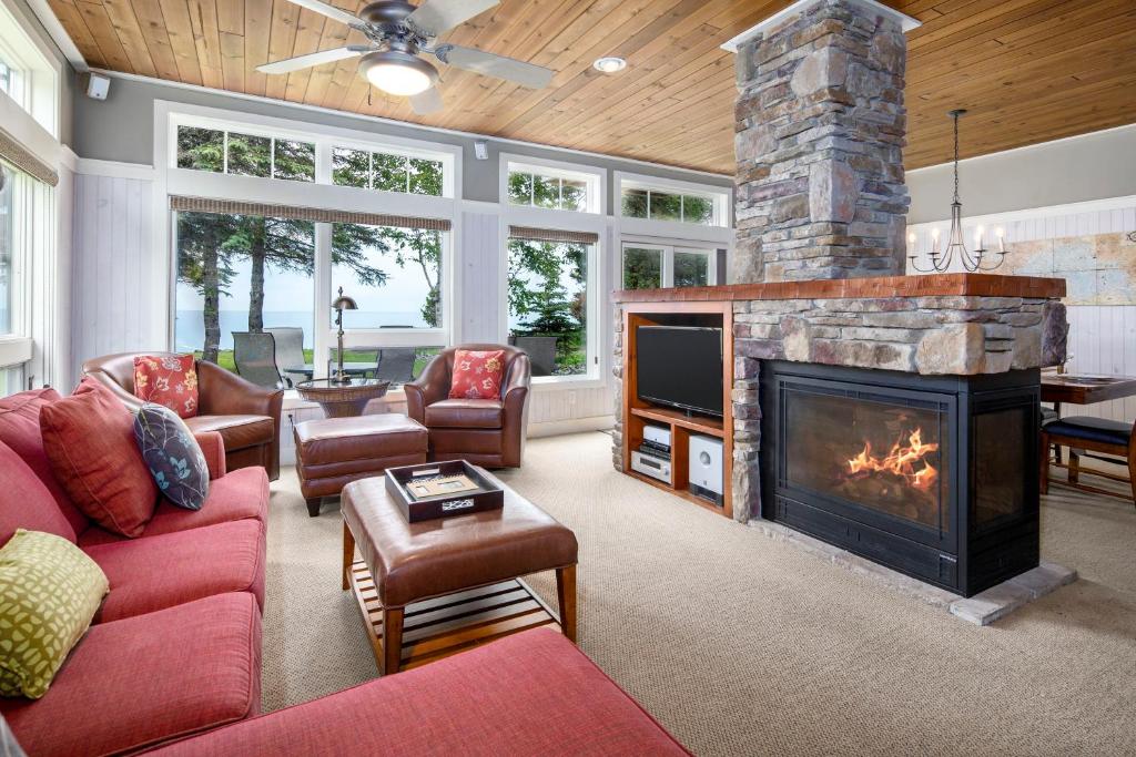 sala de estar con chimenea y muebles de color rojo en Larsmont Cottages, en Two Harbors
