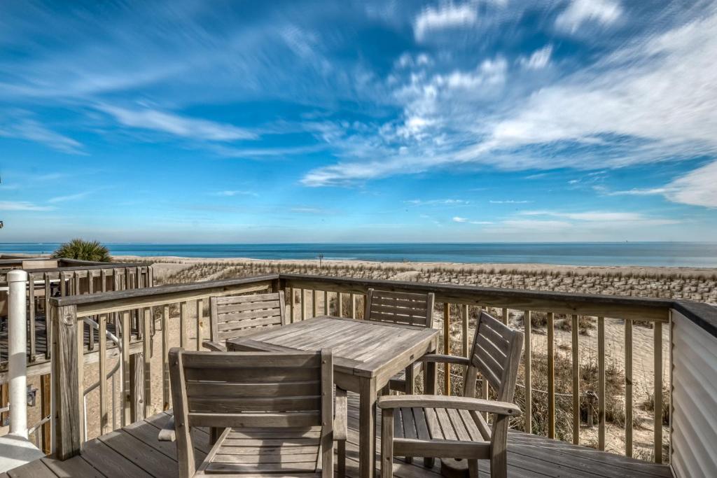 a wooden deck with a table and chairs on the beach at Tybee Lights in Tybee Island