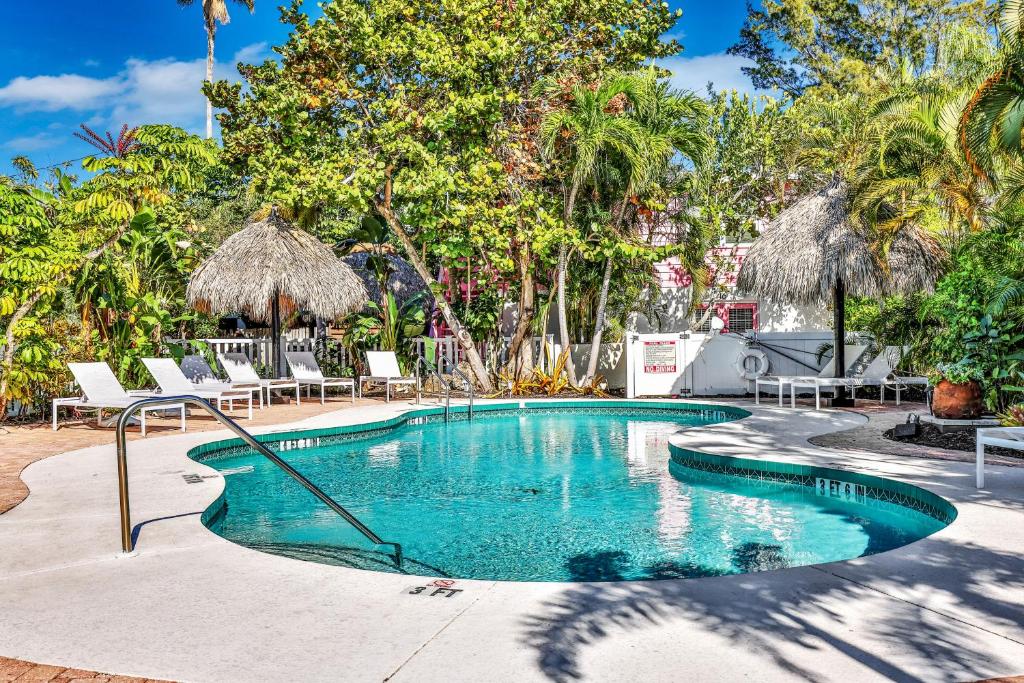 a swimming pool with chairs and trees in a yard at Sunrise Garden Resort in Anna Maria