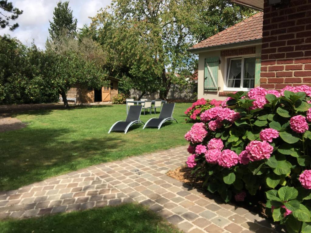 un grupo de sillas en un patio con flores rosas en Chambre d'Hotes Les Hortensias en Rang-du-Fliers