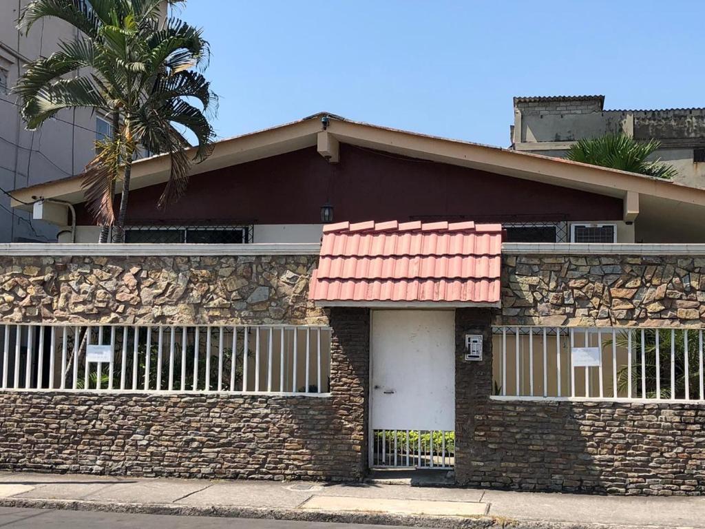 a brick house with a fence and a palm tree at Casa Violeta in Guayaquil