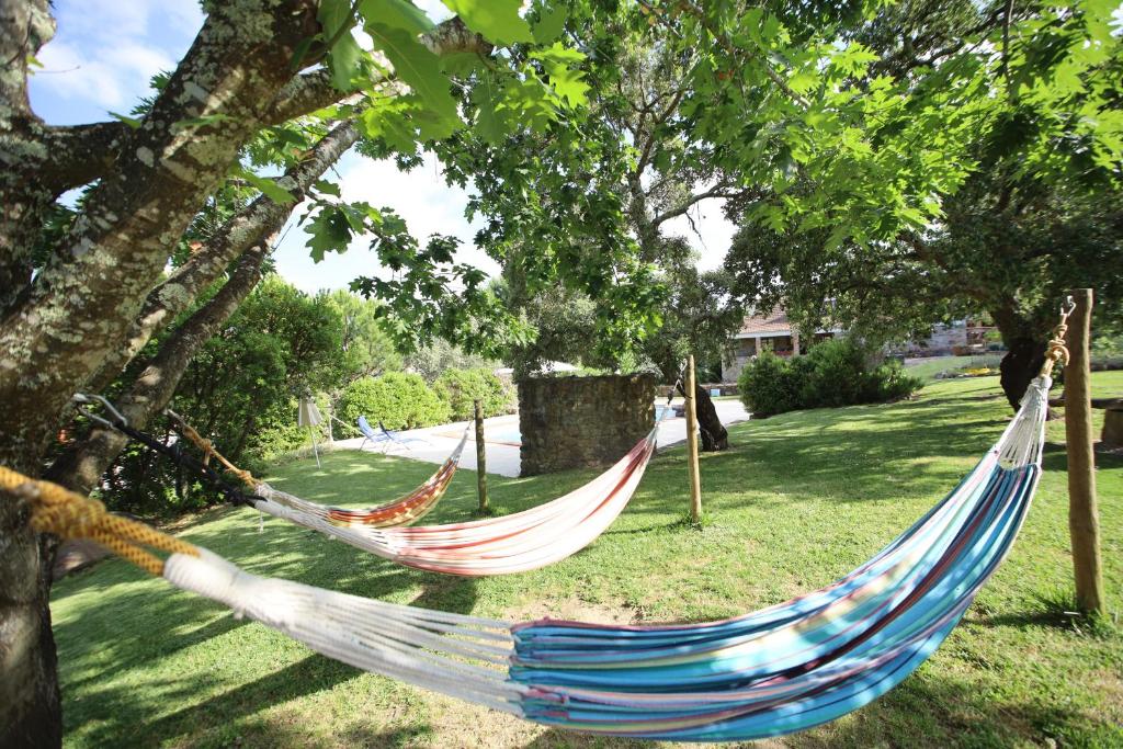 dos hamacas colgando de los árboles en un patio en Apartamentos Rurais - Casas do Lagar, en Rosmaninhal