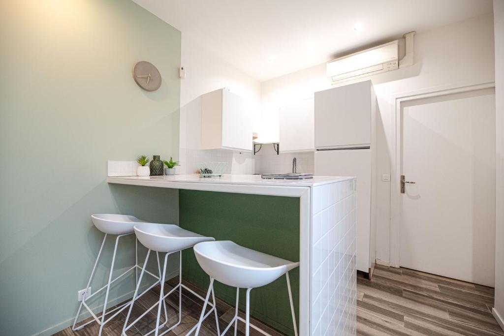 a kitchen with three stools and a counter with a sink at Lovely Home in Paris Center - AC in Paris