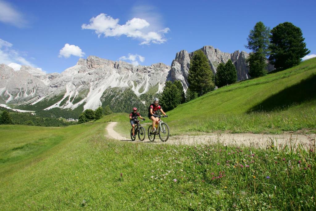 two people riding bikes on a dirt road in the mountains at Hotel Alpenroyal - The Leading Hotels of the World in Selva di Val Gardena
