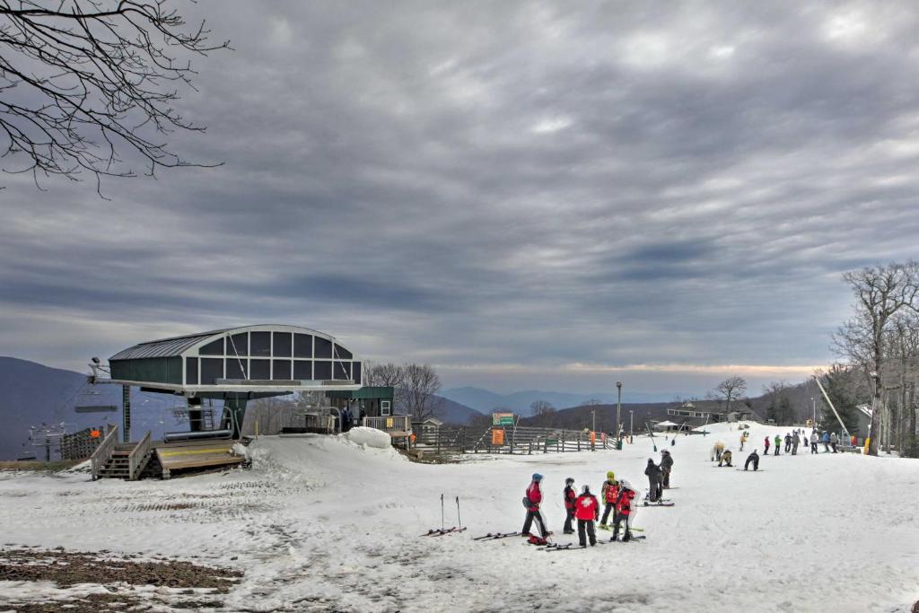 Wintergreen Home with Hot Tub, Deck and Mountain Views في Wintergreen: مجموعة من الناس يتزحلق على منحدر مغطى بالثلج