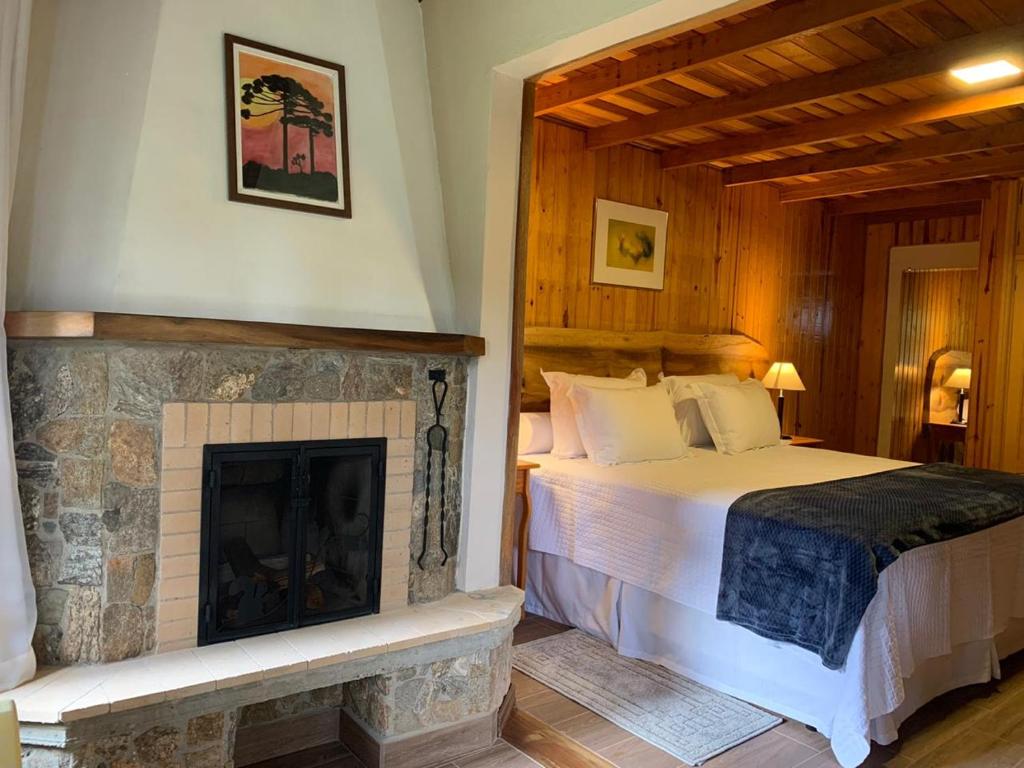 - une chambre avec un lit et une cheminée dans l'établissement Pousada Opas Haus, à Camanducaia