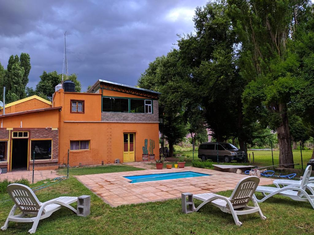 una casa con piscina y 2 sillas en el patio en Hosteria Uspallata en Uspallata