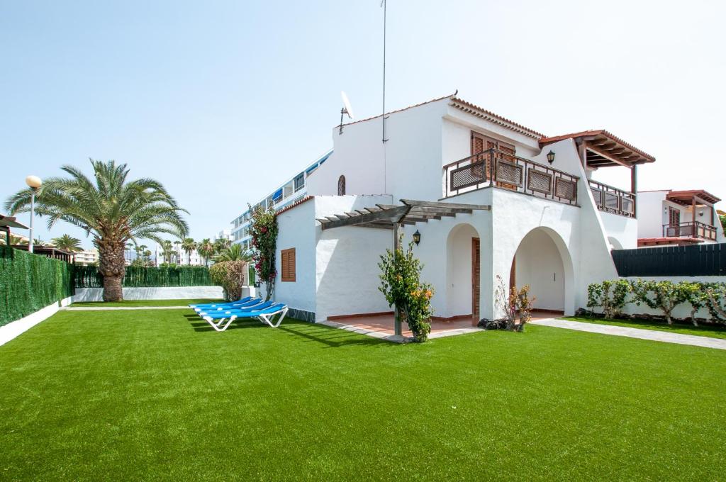 una casa bianca con un cortile con erba verde di Casalegre HOME 7 a Maspalomas