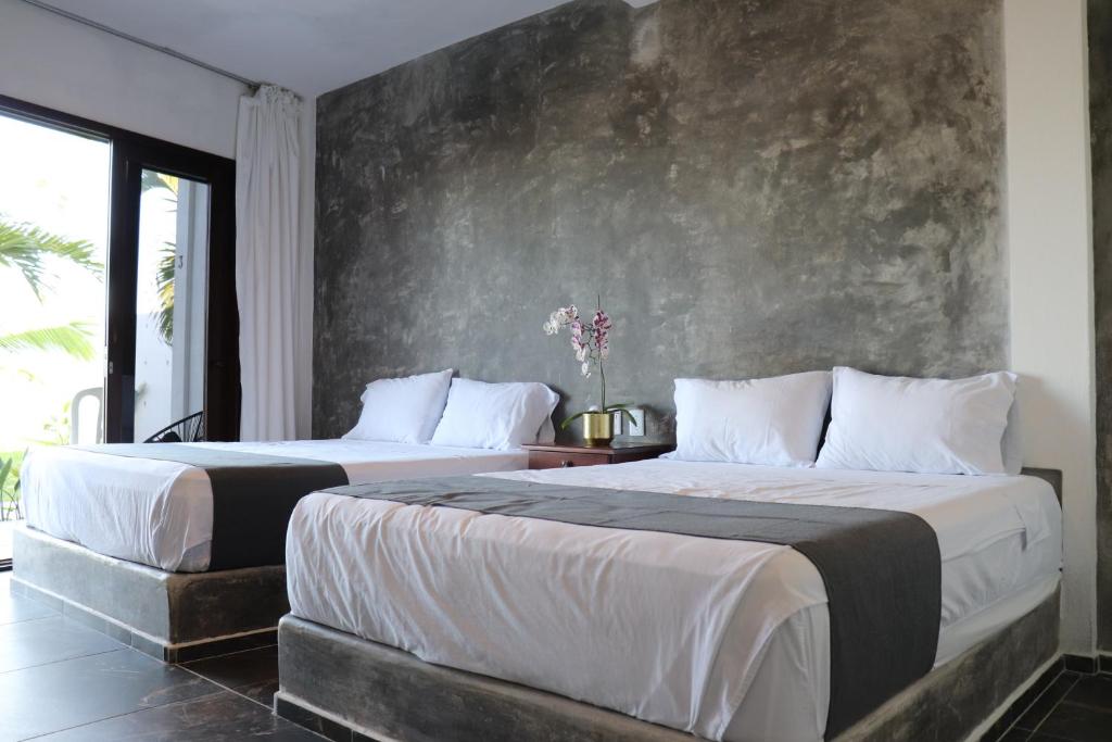 2 camas en un dormitorio con una pared de hormigón en Lunazul Hotel By Rotamundos, en La Vigueta