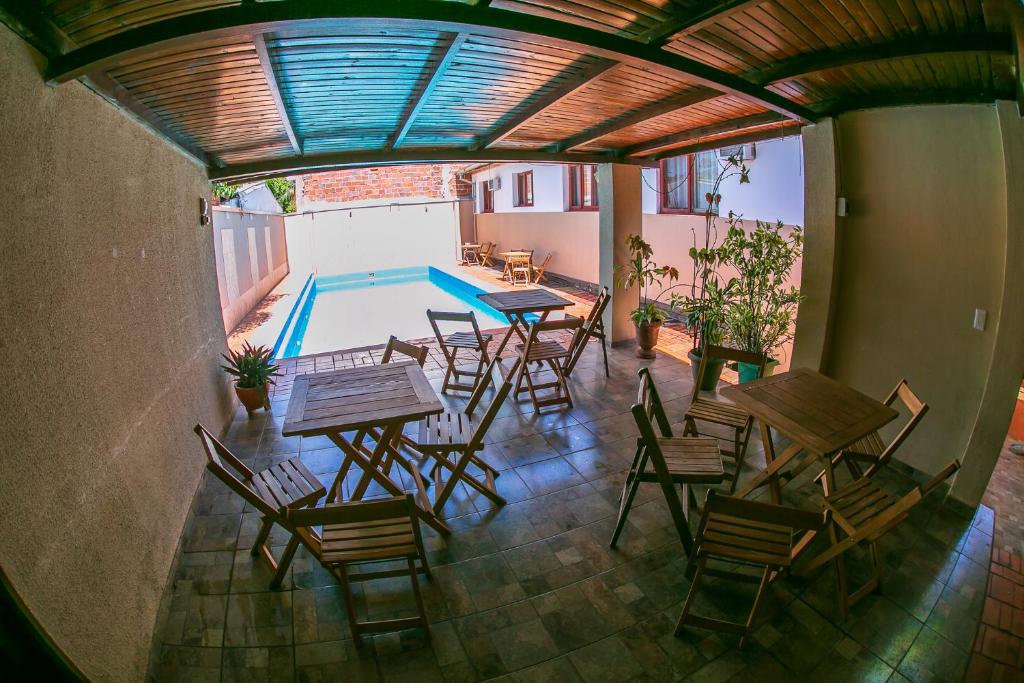 a patio with tables and chairs and a swimming pool at Hotel Tierra Colorada in Puerto Iguazú