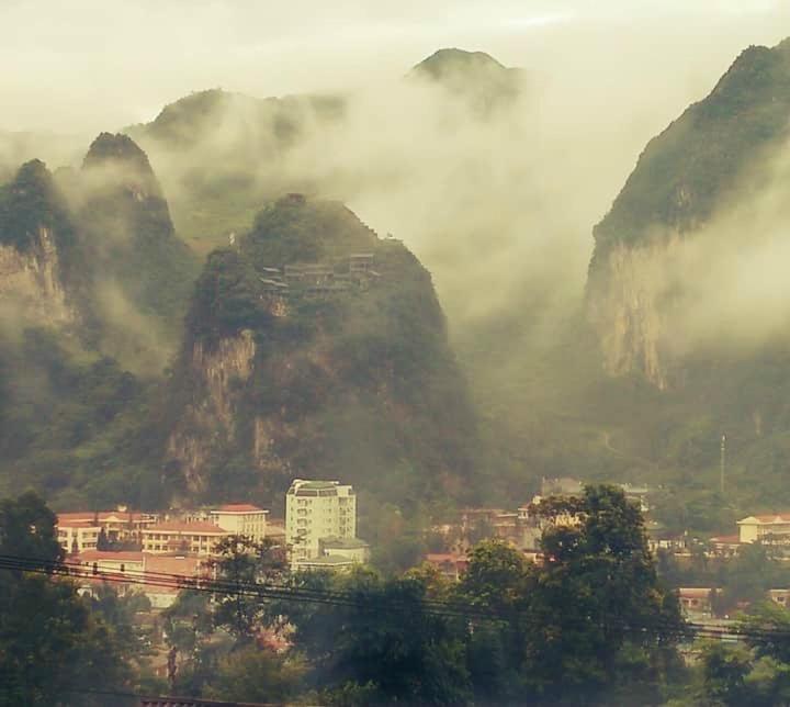 a view of a city with mountains in the fog at Hotel Cao Nguyên in Dồng Văn