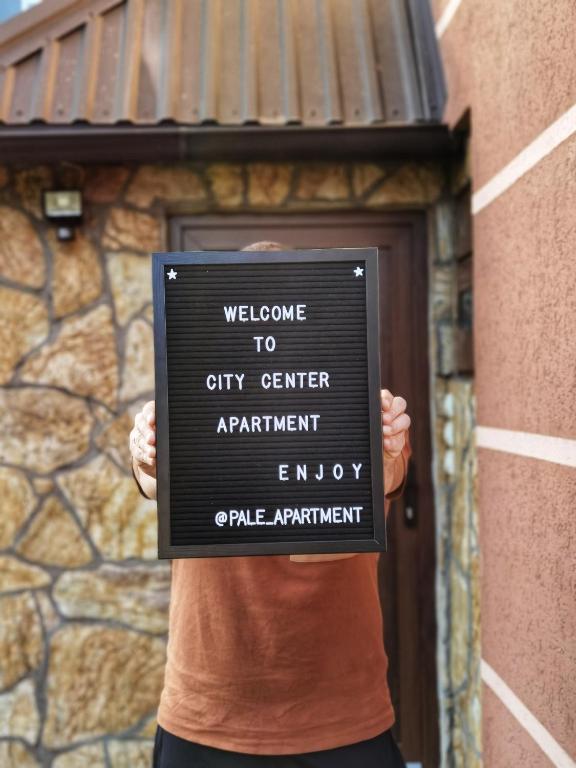 a person holding a sign in front of a building at Pale city center apartment in Pale