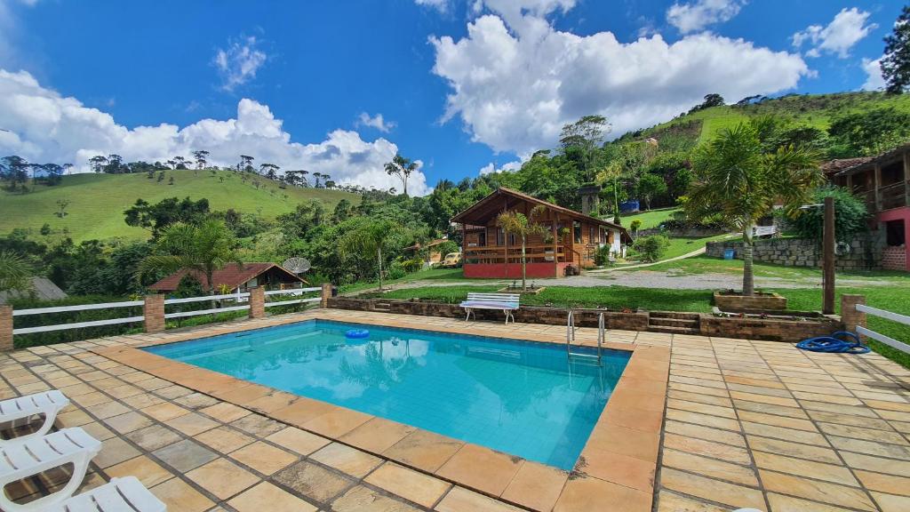 una piscina con sillas y una casa en Chales Edelweiss, en Visconde De Maua