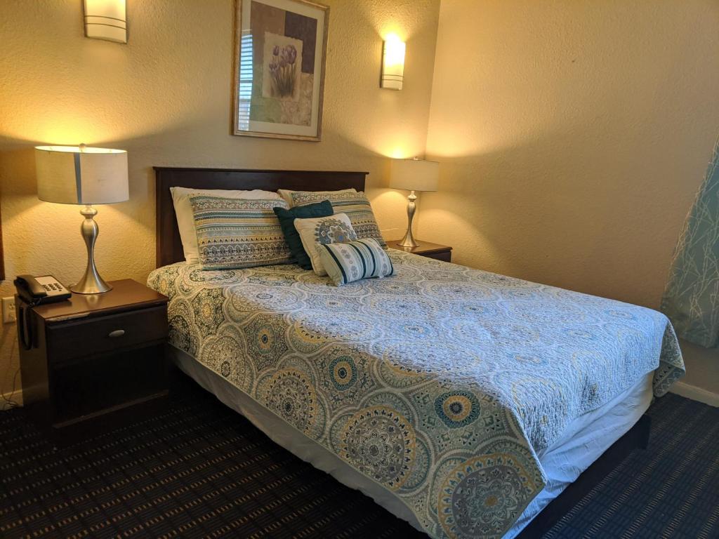 a bedroom with a bed with a blue comforter and two lamps at Athens Hotel & Suites in Houston
