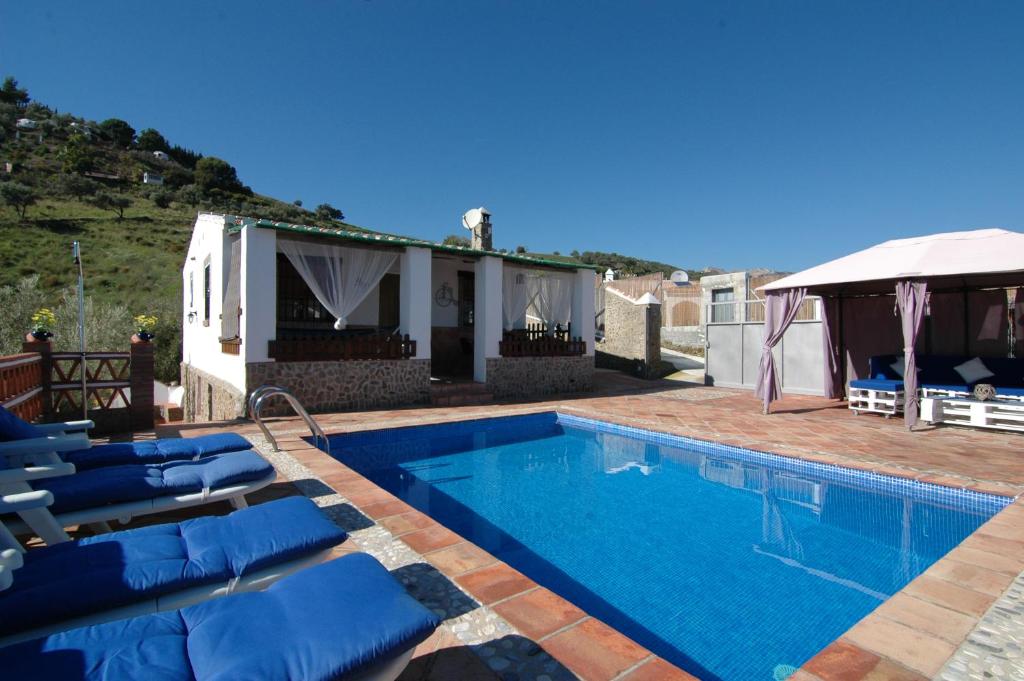 une piscine avec des chaises bleues et une maison dans l'établissement Cortijo Mirador Casitas Select, à Frigiliana
