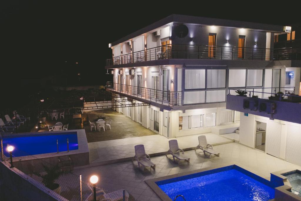 - un grand bâtiment avec une piscine la nuit dans l'établissement Vila Nikezić, à Sutomore