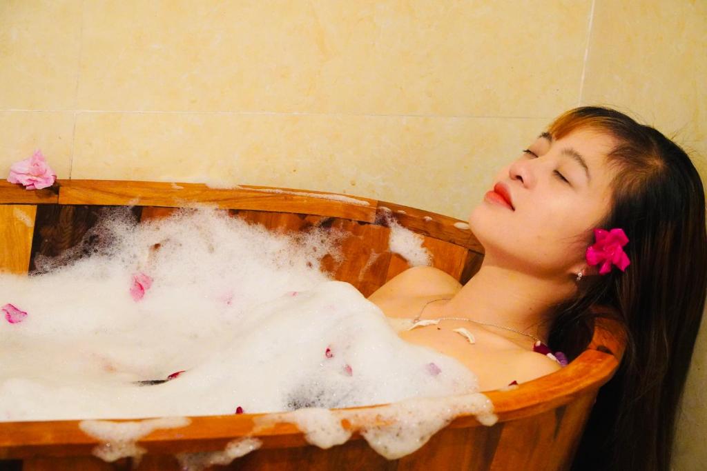 a woman is in a bath tub with bubbles at H'mong Village Resort in Ha Giang