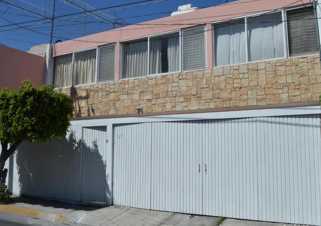 een gebouw met een witte garagedeur en een stenen muur bij LA CASA DE LOS RIVAS, AMPLIA, CÓMODA, BIEN UBICADA in Tepic