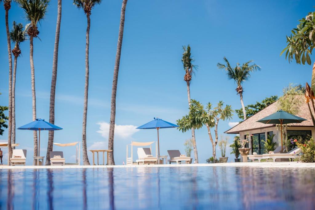 a pool with palm trees and chairs and umbrellas at New Sunari Lovina Beach Resort in Lovina