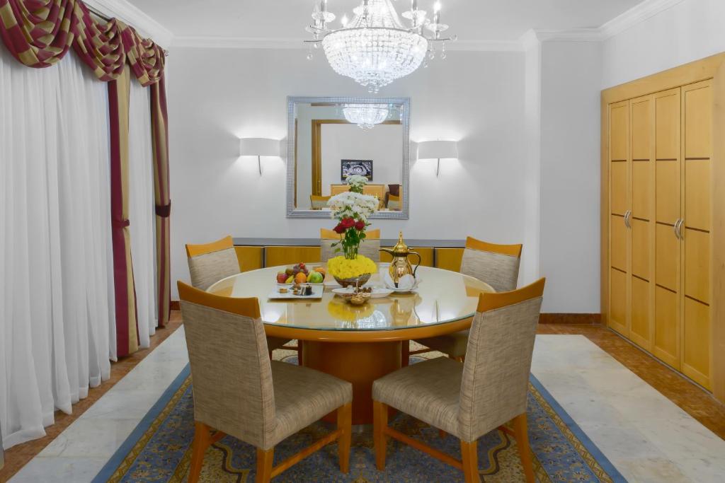 a dining room with a table with chairs and a chandelier at Makkah Towers in Mecca