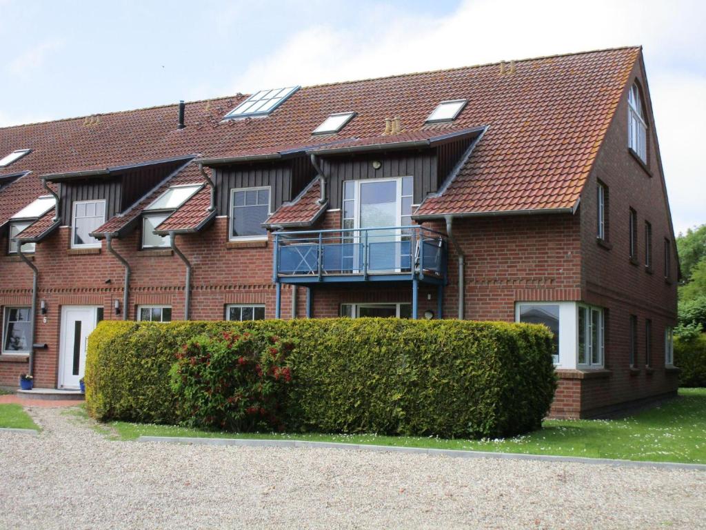 a brick house with a balcony and a bush at GODS06002-FeWo-bie-de-Reede in Gollendorf