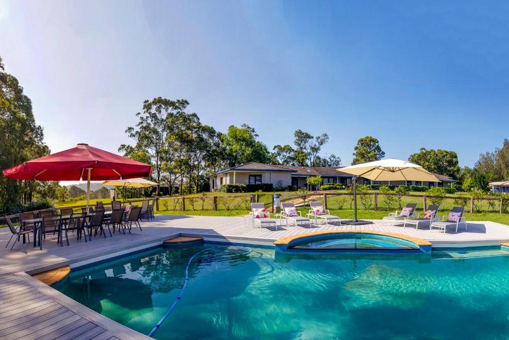 a swimming pool with chairs and tables and umbrellas at Burncroft Guesthouse in Lovedale