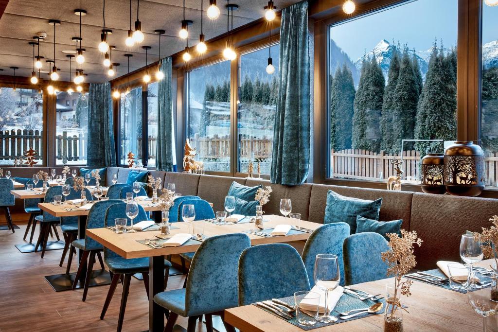 HOTEL SONNBLICK Kaprun, Salzburg - including Summer Card في كابرون: مطعم فيه طاولات وكراسي فيه جبال في الخلف