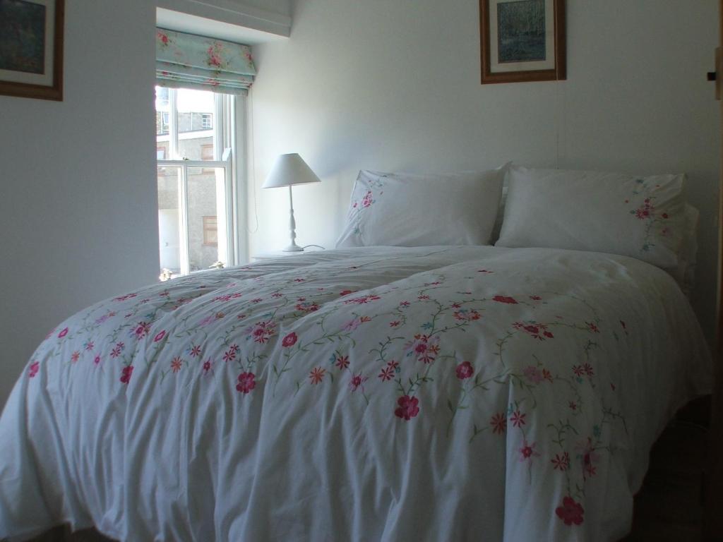 a bedroom with a white bed with flowers on it at Pen Llyn Quarryman's Cottage in Trevor