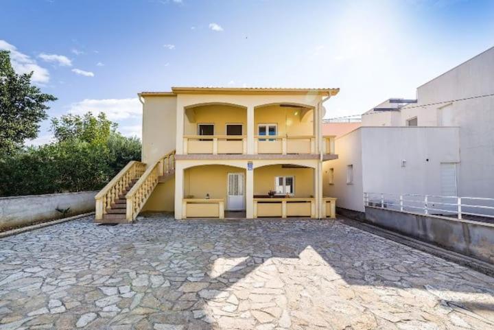 une maison jaune avec un escalier devant elle dans l'établissement Apartmani Perinić, à Vrsi